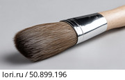 Artist's paintbrush resting on gray surface showcasing bristles and handle. Стоковое AI-изображение, AI-художник Katsiaryna Repich / Фотобанк Лори