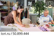 Elderly man sewing, female assistant attaching template to fabric. Стоковое фото, фотограф Яков Филимонов / Фотобанк Лори