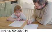 Dad teaches his son writing and counting. Kids primary education. Children learn, study in home school. Daddy male helping teaching little child boy support studying, learning homework. Knowledge day. Стоковое видео, видеограф Марина Демидюк / Фотобанк Лори