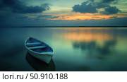 A photo of a lonely wooden boat on a smooth lake or sea surface during sunset. The soft shades of the sky are reflected in the water, creating a peaceful and meditative atmosphere. Perfectly conveys the mood of peace, solitude and harmony with nature. Suitable for website design, postcards, background images, articles about travel, freedom and inner balance. Стоковое AI-изображение, AI-художник Анна Кривицкая / Фотобанк Лори