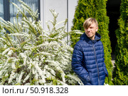 Spring Portrait: A young person in a blue jacket amidst white blossoms and green shrubbery, outdoor natural springtime serene portrait. Стоковое фото, фотограф Данила Большаков / Фотобанк Лори