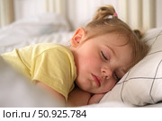 Peaceful adorable baby sleeping on a bed at home. Slumbering little child. Two years old girl sleeps peaceful at domestic room interior background. Serene dream. Cute face close up. Deep kid slumber. Стоковое фото, фотограф Марина Демидюк / Фотобанк Лори