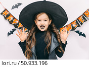 Happy funny child girl in witch costume on Halloween makes horror face and grimaces on white background. Halloween party girl. Happy Halloween Witch. High quality photo. Стоковое фото, фотограф Ирина Михайличенко / Фотобанк Лори