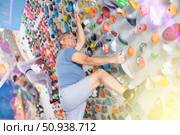 Male mountaineer climbing artificial rock wall without belay indoors. Стоковое фото, фотограф Яков Филимонов / Фотобанк Лори