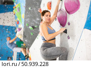 Cheerful young girl climbing artificial wall in bouldering center. Стоковое фото, фотограф Яков Филимонов / Фотобанк Лори