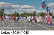 Basketball players competing during a sports day, seen through a wire mesh fence. Стоковое видео, видеограф Mikhail Davidovich / Фотобанк Лори