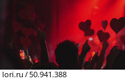 Crowd of hands holding red heart-shaped signs at a vibrant concert with dramatic lighting effects. Стоковое видео, видеограф Данил Руденко / Фотобанк Лори