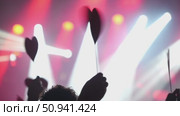 Hands holding heart-shaped signs at a vibrant concert with colorful lights and energetic atmosphere. Стоковое видео, видеограф Данил Руденко / Фотобанк Лори
