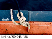 Close-up of mooring rope with knotted end tied around cleat on pier equipment. Стоковое фото, фотограф Spirit River / Фотобанк Лори