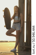 A woman is holding a skateboard and standing in front of a fence. Стоковое видео, видеограф Константин Шишкин / Фотобанк Лори