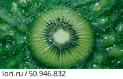 A close-up of kiwi slice immersed in bubbling liquid. Стоковое AI-изображение, AI-художник Данила Большаков / Фотобанк Лори