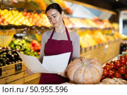 Middle-aged female seller restocking with paper in grocery market. Стоковое фото, фотограф Яков Филимонов / Фотобанк Лори
