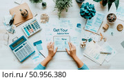 Overhead view of hands interacting with a digital tablet displaying 'Get Your Advice Now' text, surrounded by financial papers, calculators, and potted plants on a tidy desk, ideal for a financial se. Стоковое AI-изображение, AI-художник Данила Большаков / Фотобанк Лори