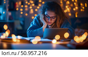Young woman studying intently at her illuminated desk during a cozy evening, surrounded by a magical glow of warm festive lights, capturing a peaceful moment of contemplation. Стоковое AI-изображение, AI-художник Данила Большаков / Фотобанк Лори