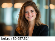 A confident young woman with natural makeup and a warm smile stands in a modern office setting. Her professional attire and relaxed expression convey poise and approachability. Стоковое AI-изображение, AI-художник Nart / Фотобанк Лори
