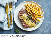 Closeup of grilled steak with French fries and creamy mustard sauce on a ceramic plate. High-protein restaurant-style dish, perfect for advertising lunch menus, takeout, or food delivery services. Стоковое AI-изображение, AI-художник Евгений Демидюк / Фотобанк Лори