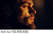 Close-up profile of a man with a beard bathed in a warm, golden glow, evoking a pensive and strong demeanor, suitable for a striking artistic impression. Стоковое AI-изображение, AI-художник Данила Большаков / Фотобанк Лори