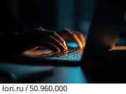 Person typing at laptop computer at night. Female uses keyboard, shakes buttons with fingers. Internet security, cyber attack. Trendy neon light. Creative dark color of orange, black, and teal blue. Стоковое AI-изображение, AI-художник Марина Демидюк / Фотобанк Лори