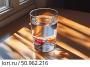 A glass of clean water with multi-colored capsules inside, against the backdrop of soft sunlight coming through the window. The warm atmosphere and morning light create associations with health care, the beginning of the day, medicine and taking vitamins or medications. A perfect visual for themes about pharmaceuticals, healthy lifestyle and self-care. Стоковое AI-изображение, AI-художник Анна Кривицкая / Фотобанк Лори
