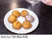 A baker dusts homemade muffins with powdered sugar, adding a subtle sweetness and decorative touch. Стоковое фото, фотограф Коханова Наталья / Фотобанк Лори