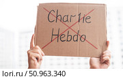 2 November 2020 France Paris: A man holds a cardboard poster with charlie hebdo crossed out. Редакционное фото, фотограф Михаил Решетников / Фотобанк Лори