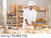 Adult male baker kneading dough on table. Стоковое фото, фотограф Яков Филимонов / Фотобанк Лори
