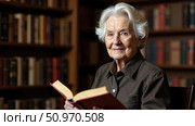 Warm portrait of an elegant gray-haired grandmother holding a book in a library, symbolizing intergenerational support and respect for the elderly. Heartwarming concept of care. Стоковое AI-изображение, AI-художник Светлана Леуто / Фотобанк Лори