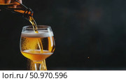 A golden amber liquid stream fills a radiant glass with frothy foam in a dark setting. Стоковое AI-видео, аниматор Данила Большаков / Фотобанк Лори