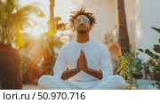 Person meditates outdoors in sunlight with hands in prayer position wearing dreadlocks, sunglasses, and a white outfit. Стоковое AI-видео, аниматор Данила Большаков / Фотобанк Лори