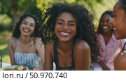 A joyful gathering: a young african woman's radiant smile at an outdoor brunch with friends, embodying happiness and connection amidst nature's beauty. Стоковое AI-видео, аниматор Данила Большаков / Фотобанк Лори