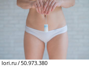 Faceless woman in white panties holds a tampon. Female absorbent hygiene product. Comfort and freedom during regular periods. Approved by a gynecologist. Стоковое фото, фотограф Михаил Решетников / Фотобанк Лори