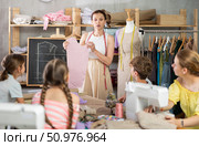 Female teacher at the blackboard explains to children how to make patterns and sew dress. Стоковое фото, фотограф Яков Филимонов / Фотобанк Лори