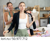 Young tailoress trying ready jacket on female client. Стоковое фото, фотограф Яков Филимонов / Фотобанк Лори