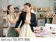 Young tailoress trying ready jacket on female client. Стоковое фото, фотограф Яков Филимонов / Фотобанк Лори