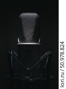 A professional studio microphone captured in moody low-key lighting, perfect for voiceovers, podcasts, or music production. Стоковое фото, фотограф Happyphotons / Фотобанк Лори
