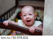 Infant Emotions: Crying Baby in Crib - Motherhood and Parenting in Early Childhood Development. Стоковое фото, фотограф Максимова Марина / Фотобанк Лори