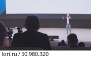 Audience observing a speaker presenting on stage in a conference setting. Стоковое видео, видеограф Антон Гвоздиков / Фотобанк Лори