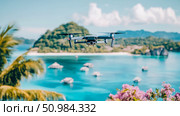 DJI Mavic Drone Hovering Above a Vibrant Tropical Island Paradise with Azure Waters, Lush Palms, and Distant Mountains. Стоковое AI-изображение, AI-художник Данила Большаков / Фотобанк Лори