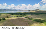 Bannoe Center, Russian Federation - July 27, 2025: Expansive golden grassland landscape under a bright blue sky with fluffy clouds and distant mountains, showcasing the beauty of nature and tranquility. Редакционное видео, видеограф Ирина Ручушкина / Фотобанк Лори