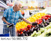 Elderly retired man buying eggplants in grocery section of the supermarket. Стоковое фото, фотограф Татьяна Яцевич / Фотобанк Лори