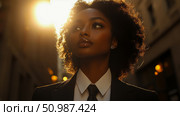 Radiant Black Woman in Professional Attire with Golden Backlight, Gaze Fixed Upward, Portraying Confidence and Future Aspirations. Стоковое AI-изображение, AI-художник Данила Большаков / Фотобанк Лори