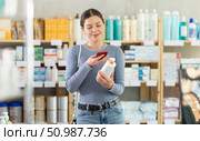 Young woman scanning QR-code on cream in drugstore. Стоковое фото, фотограф Яков Филимонов / Фотобанк Лори