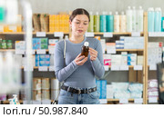 Young girl customer choosing syrup in drugstore. Стоковое фото, фотограф Яков Филимонов / Фотобанк Лори