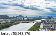 Urban landscape. View from the observation deck. Automobile bridge over the river. Green vegetation on the shores. There are many multi-storey city buildings. A theater with a beautifully curved roof. Стоковое фото, фотограф Вера Ивановна Кубарева / Фотобанк Лори