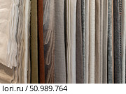 A collection of various fabric swatches in neutral tones. The fabrics include linen, cotton, and silk, arranged neatly in vertical rows. Стоковое фото, фотограф PAv / Фотобанк Лори