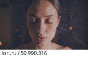 Young woman meditating with closed eyes in a dimly lit room, enveloped in swirling incense smoke, fostering a serene and tranquil ambiance that enhances her spiritual practice. Стоковое AI-видео, аниматор Данил Руденко / Фотобанк Лори