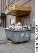 Dumpster full of construction debris in front of building under renovation. Стоковое фото, фотограф Юрий Поздников / Фотобанк Лори