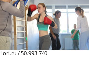 Teen girl works out strength and speed of boxing punch mitts with help of partner in boxing paws. Стоковое видео, видеограф Яков Филимонов / Фотобанк Лори