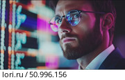 Focused young professional analyzes stock market data in a modern trading environment. Стоковое AI-видео, аниматор Сергей Толмачёв / Фотобанк Лори