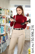 European woman holds induction surface cleaners and glass-ceramics in her hands in a household store. Customer looks at the labels of cleaning products. Стоковое видео, видеограф Яков Филимонов / Фотобанк Лори